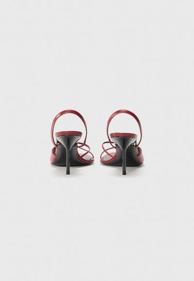 Sandalias de tacón alto rojas con tiras, con un elegante tacón de aguja negro y un acabado suave y brillante. El diseño de espalda descubierta revela tiras ajustables.