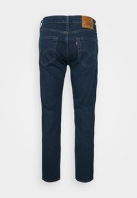 Mörkblå jeans i denim med rak skärning, utrustade med två bakfickor och en brun läderlapp vid midjebandet.