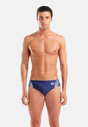 Slip de bain homme bleu marine avec un motif texturé blanc sur les côtés. Confectionné en matière extensible pour le confort et la performance.