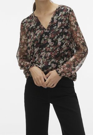 Gennemsigtig sort bluse med blomstermønster i nuancer af pink, rød og grøn. Har en V-halsudskæring og lange, puffede ærmer med elastiske manchetter.