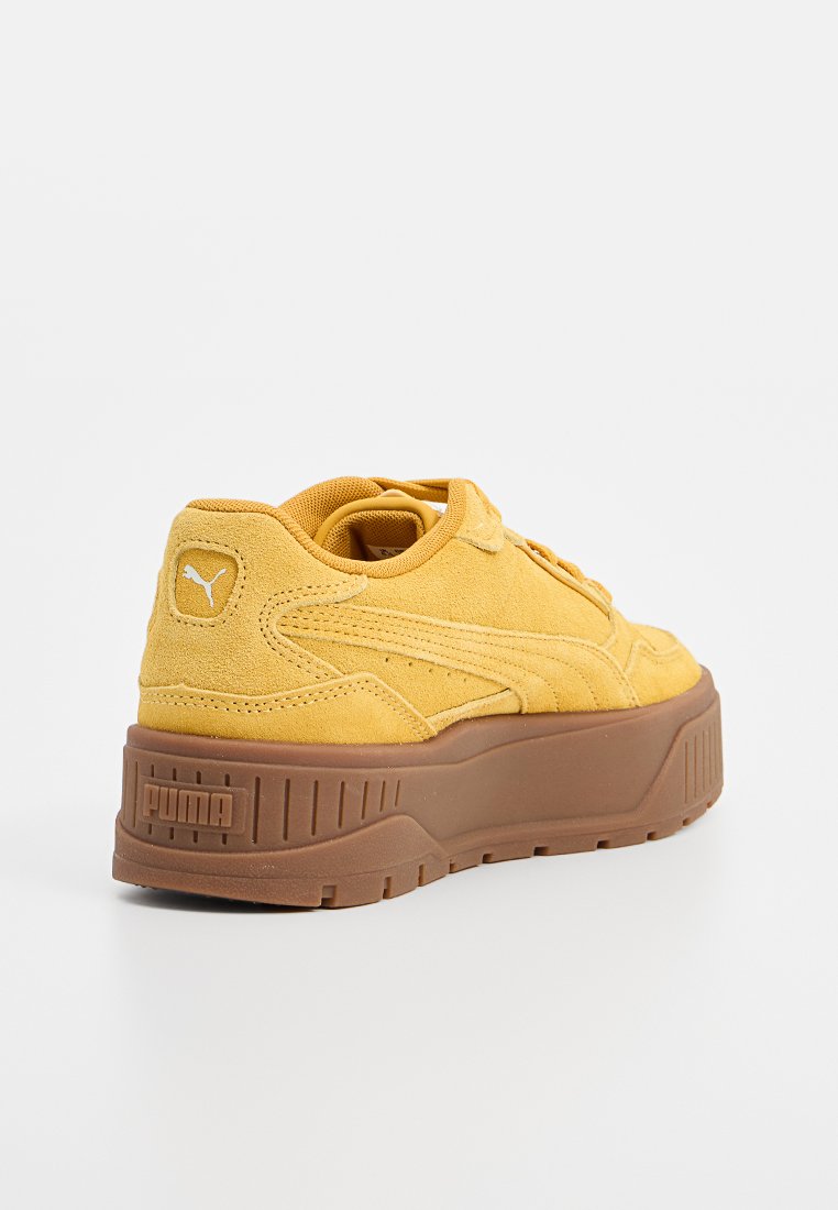 Zapatillas de ante amarillas con una gruesa suela de goma marrón y acentos texturizados. Cuenta con un collar acolchado y un logo en el talón.