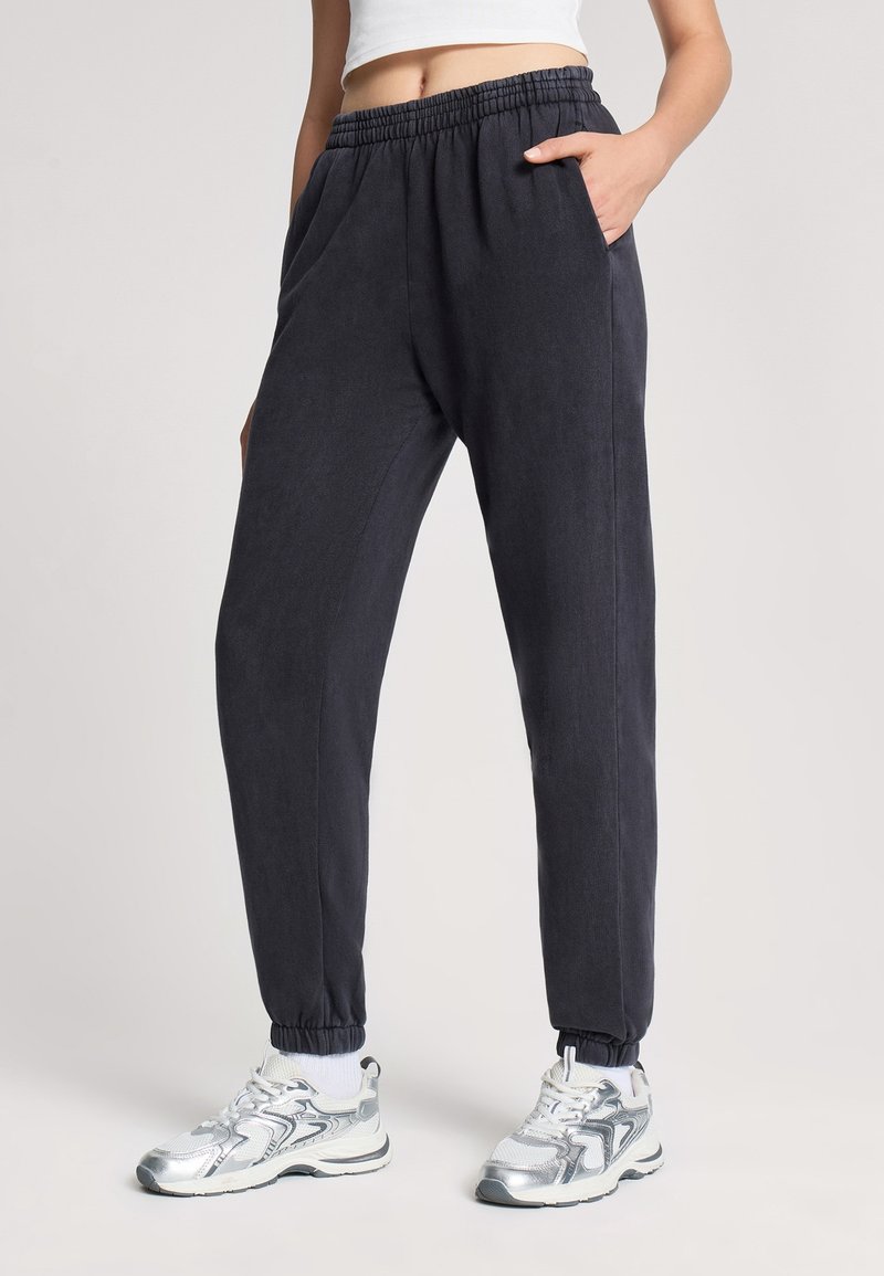 Ciemnogranatowe spodnie dresowe z elastycznym pasem, bocznymi kieszeniami i zwężanymi nogawkami, wykonane z miękkiego, lekkiego materiału.