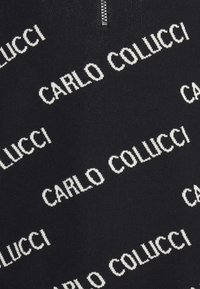 Čierny sveter z pleteniny s opakovaným bielym textom "CARLO COLUCCI" v rôznych orientáciách, s golierom na zips.
