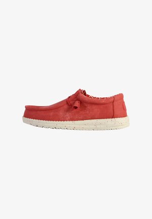 Scarpa slip-on rossa con superficie testurizzata, punta rotonda e suola maculata bianca. Presenta un piccolo dettaglio a fiocco sulla parte superiore.