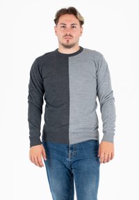 Szary i węglowy sweter w dwóch odcieniach z okrągłym dekoltem, ściągaczami przy rękawach i u dołu. Noszony z niebieskimi dżinsami. Miękka, gładka tekstura dzianiny.