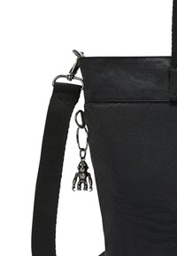 Zwarte handtas met een korte strap en een glanzend zwart aapje als sleutelhanger aan een sluiting. Beschikt over een gladde afwerking en een hedendaags ontwerp.