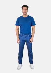 Camiseta de algodón azul, vaqueros de denim azul, zapatillas blancas. Diseño ajustado con pequeños detalles de costura y estilo clásico de cinco bolsillos.