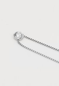 Silberkette mit rundem Anhänger, der einen klaren Stein enthält, verbunden durch eine zarte Kette mit ineinandergreifenden Gliedern.