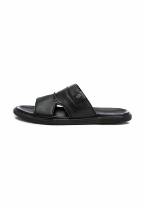 Sandalia de slide de cuero negro con un diseño de tiras cruzadas, detalles texturizados y una suela de goma. Presenta un pequeño logotipo en la tira.