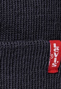 Marineblauw gebreide stof met een gestructureerd patroon, met een rode Levi's-tag prominent aan de zijkant weergegeven.