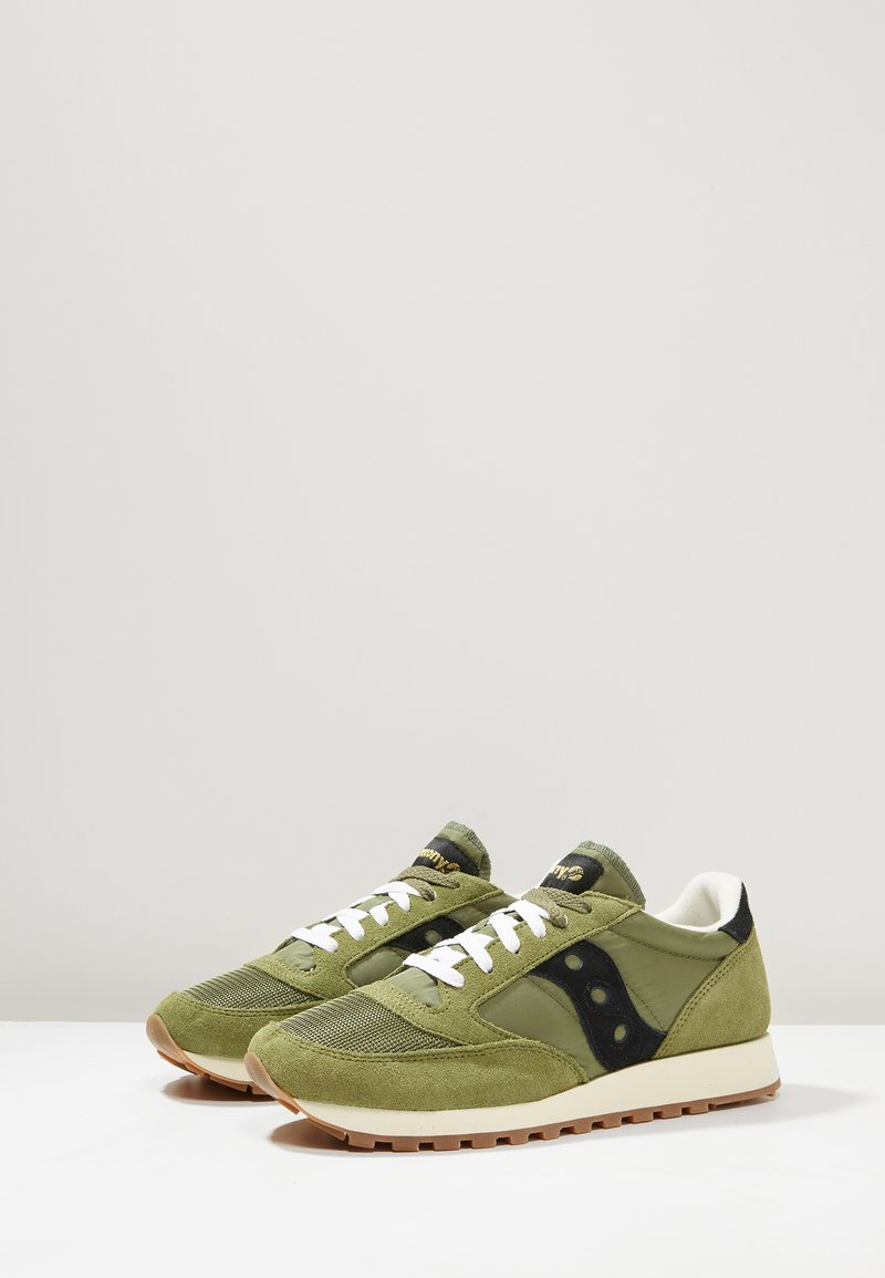 Groene suède en mesh sneakers met witte veters, zwarte accenten en een rubberen zool. Ronde neus en textuurpanelen.
