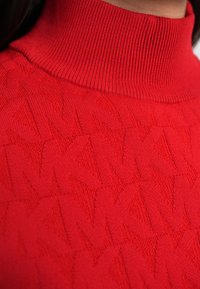 Pulover roșu cu guler înalt, realizat din material tricotat, având un model texturat pe întreaga suprafață și un detaliu cu guler reiat.