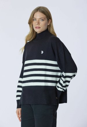 Maglione a collo alto a righe bianche e nere con una trama a coste, vestibilità ampia e piccolo dettaglio logo sul petto.