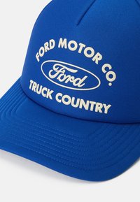 Mėlyna beisbolo kepurė su balta užrašu ir Ford logotipu, ant priekinės panelės rašoma "Ford Motor Co. Truck Country".