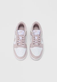 Valkoiset ja vaaleanpunaiset Nike-tennarit. Varustettu rei'itetyllä varpaan alueella, pehmustetulla kauluksella ja nauhoilla. Pinnat koostuvat sileästä nahasta ja verkkomateriaalista.