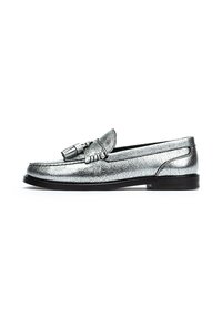 Mocasines plateados metálicos con un acabado texturizado, que presentan un detalle de borlas en el frente, puntera redonda y una suela negra baja.