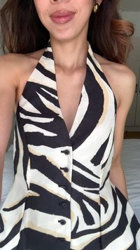 Halterneck-Bluse mit tiefem V-Ausschnitt, in schwarz-weißem Zebramuster und beigefarbenen Akzenten. Knopfverschluss an der Vorderseite, leichtes Material.
