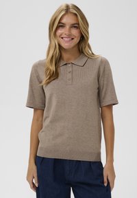 Šviesiai ruda megzta polo marškinėliai su apykakle ir trimis mygtukais. Trumpomis rankovėmis, raukiniais apatinėje dalyje ir minkšta tekstūra, tinkama kasdienei aplinkai.