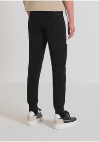 Zwarte joggingbroek met elastische boorden, met een zijzak en een witte streep aan de zijkant. Gemaakt van zachte stof voor comfort.