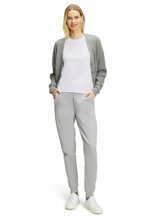 Grau strukturiertem Cardigan über einem weißen T-Shirt, kombiniert mit grauen Jogginghosen und weißen Sneakers. Das Outfit hat eine lässige Passform.