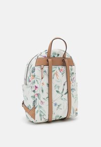 Sac à dos fleuri avec une surface texturée blanche, des accents en cuir marron et deux poches latérales. Dispose d'un dessus arrondi et de bretelles réglables.