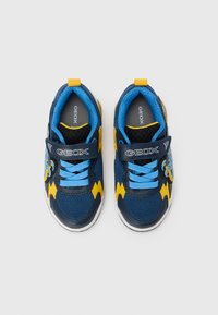 Μπλε και κίτ�ρινα αθλητικά παπούτσια με ύφασμα από δίχτυ, επενδεδυμένο περιλαίμιο και ιμάντα Velcro. Διαθέτουν διακοσμητικές λεπτομέρειες και λαστιχένια εξωτερική σόλα για πρόσφυση.