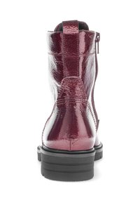Bordeaux enkellaars met lakleren afwerking, ronde neus, rits aan de achterkant en een zwarte rubberen zool. Bevat een treklipje aan de achterkant.