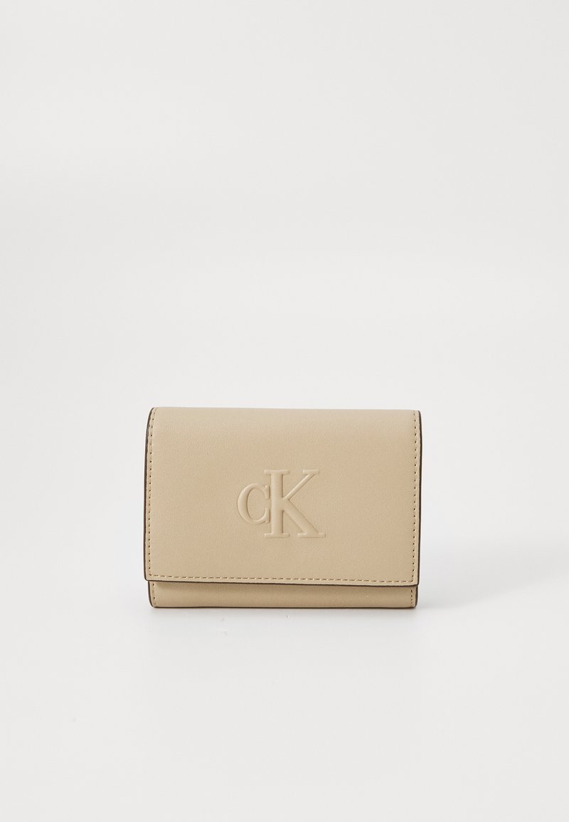 Portefeuille en cuir beige avec le logo "cK" en relief, de forme rectangulaire, texture douce et coutures visibles le long des bords.