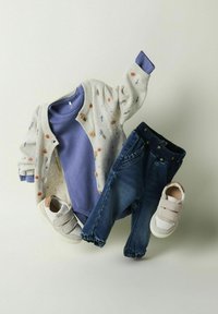 Cárdigan gris claro con bordados florales, camiseta de manga larga morada, jeans azul oscuro y zapatillas beige con tiras de velcro.