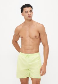Lime zöld úszónadrág rugalmas derékkel és zsinórral, bal lábon egy kis logóval. Könnyű, sima anyag.