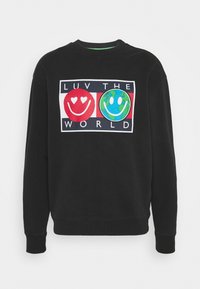 Felpa nera con grafica frontale che presenta due faccine sorridenti e il testo "LUV THE WORLD" nei colori rosso, bianco, blu e verde.