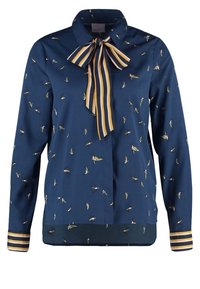 Marinblus med fågelmönster, krage, snördång och randiga manschetter. Slät tyg med en subtil lyster och avslappnad passform.