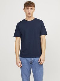 T-shirt en coton bleu marine avec un col rond et des manches courtes, associé à un jean bleu clair. Design minimaliste, texture lisse.