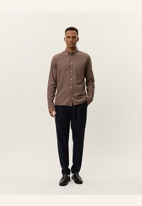 Bruin en wit geblokt overhemd met lange mouwen, gecombineerd met donkerblauwe broek en zwarte schoenen, voorzien van een button-down kraag en een rechte pasvorm.