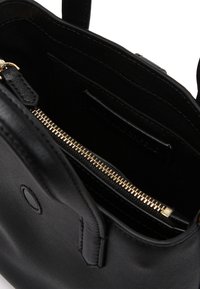 Εσωτερικό από μαύρο δερμάτινο τσάντα με λεία υφή. Διαθέτει χρυσό φερμουάρ και μία μικρή τσέπη. Μινιμαλιστικός σχεδιασμός, χωρίς ορατά σχέδια.