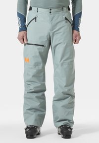 Lichtgroene waterdichte skibroek met ritszakken en een verstelbare taille; oranje logo op de linker dij; gladde, duurzame stof.