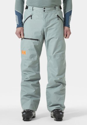 Pantalones de esquí impermeables de color verde claro con bolsillos con cremallera y cintura ajustable; logo en naranja en el muslo izquierdo; tela suave y duradera.