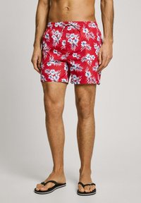 Shorts de bain rouges avec un motif floral bleu et blanc, taille élastique avec cordon de serrage, longueur au-dessus du genou, texture de tissu lisse.