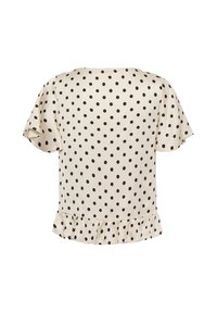 Blouse crème à manches courtes avec des pois noirs et un ourlet volanté, vue de dos.