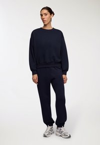 Granatowa bluza i dresy wykonane z miękkiej mieszanki bawełny, z prążkowanymi mankietami i paskiem w talii, w połączeniu ze srebrnymi sneakersami.