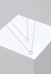 Collane a più strati in tono argento, che presentano due catene con pendenti circolari. Le catene hanno un design delicato e testurizzato.
