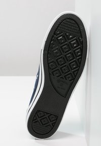 Baskets en toile bleu marine avec semelle en caoutchouc blanche. Dotées d'une semelle extérieure noire texturée à motif diamant et d'œillets latéraux. Design classique.