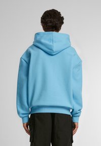 Felpa blu con grande cappuccio, maniche lunghe e vestibilità comoda. Presenta polsini e orlo a coste, realizzata in morbido cotone.