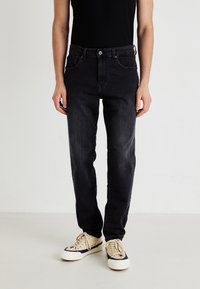 Mustat farkut slim fit -leikkauksella, viidellä taskulla ja napitus. Yhdistetty beigeihin tennareihin ja tiukkaan mustaan toppiin.