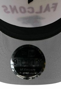 Graue A-Frame-Kappe mit schwarzem Schirm. Verfügt über ein rundes, reflektierendes Etikett mit der Aufschrift "9FORTY M-CROWN Adjustable." Das Innenfutter ist weiß mit Text.