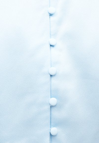 Tissu bleu clair présentant une rangée verticale de six boutons recouverts au centre.