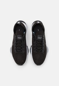 Černé tenisky s texturovaným svrchním materiálem z semiše, šněrováním, bílou gumovou podrážkou a perforovanými detaily. Obsahují modrý akcent na vnitřní straně.