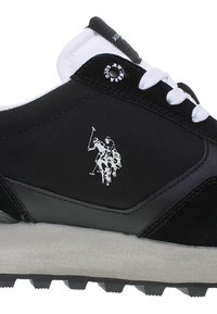 Musta tennari, joka on valmistettu nahasta ja mokasta, valkoisilla nauhoilla, valkoisella kaulalla, ja sivussa on huomattava logo polo-pelaajasta.