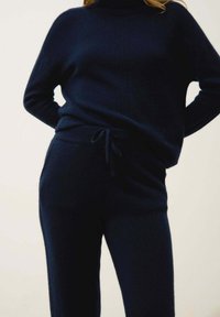 Navy stickad tvådelad outfit med en polotröja med vertikala ribbningar och byxor med dragsko för en avslappnad passform.