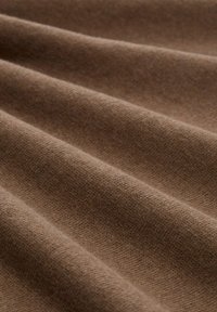 Brauner Stoff mit einer weichen Textur, der feine Rippungen und Falten aufweist und eine einheitliche Farbe sowie ein leichtes Erscheinungsbild zeigt.